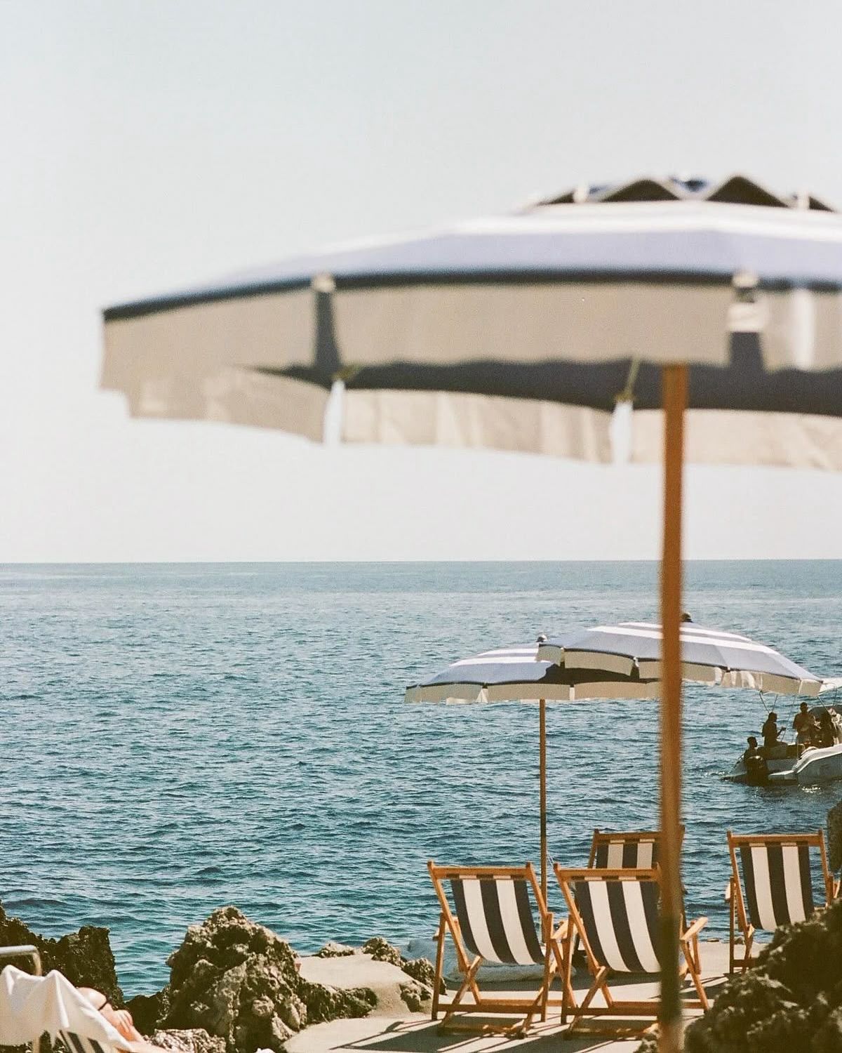 Beach scene with striped deck chairs and umbrellas overlooking the ocean.